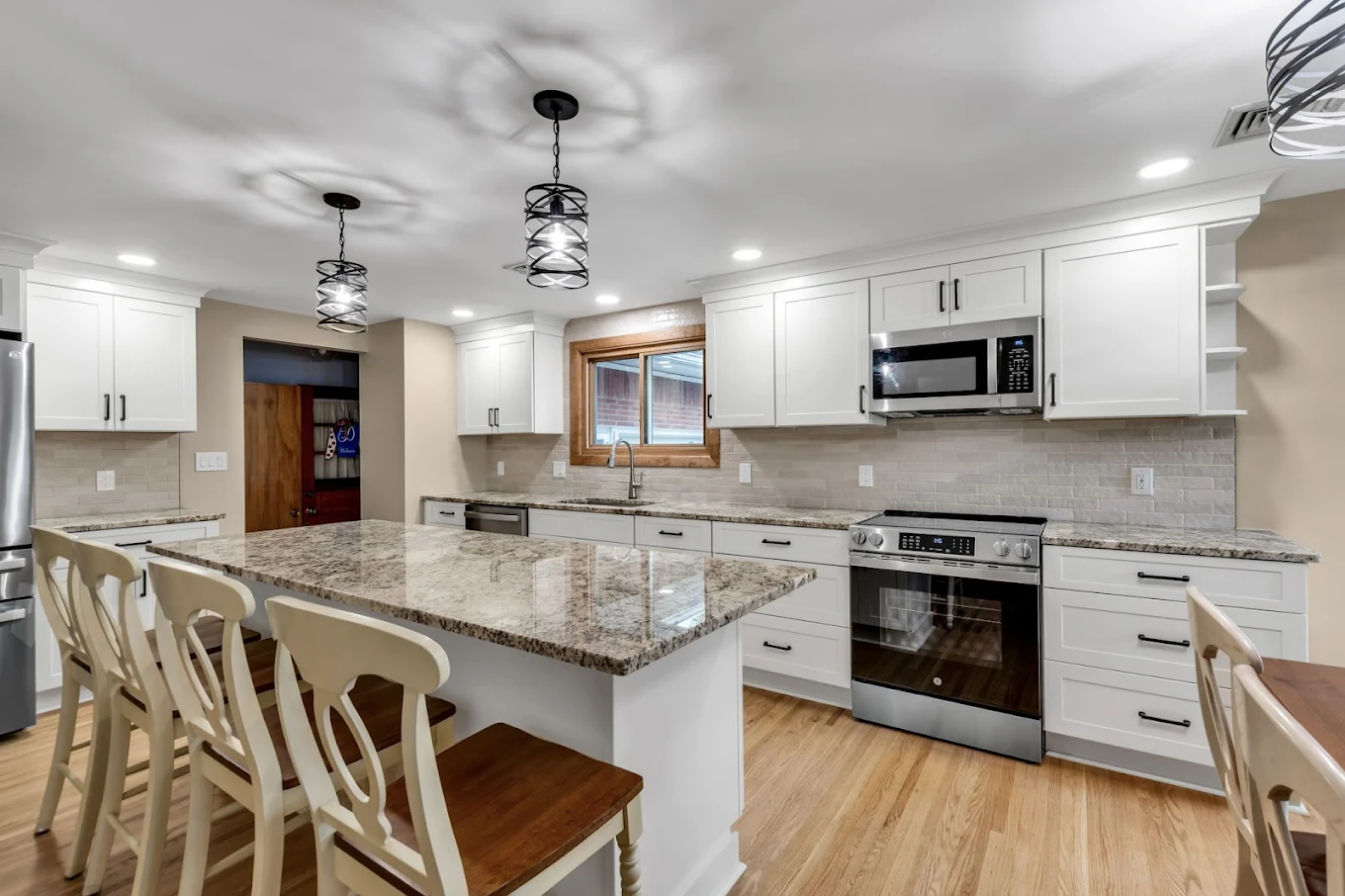 White Kitchen with Granite Counters and Cage Pendants - Sireika Renovations
